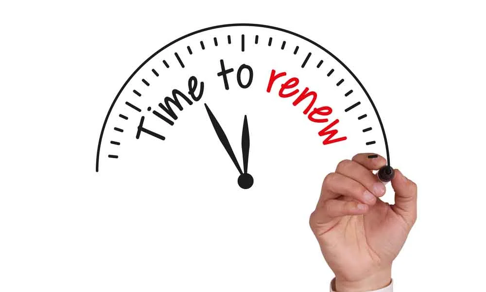 A hand drawing a clock face with the words time to renew